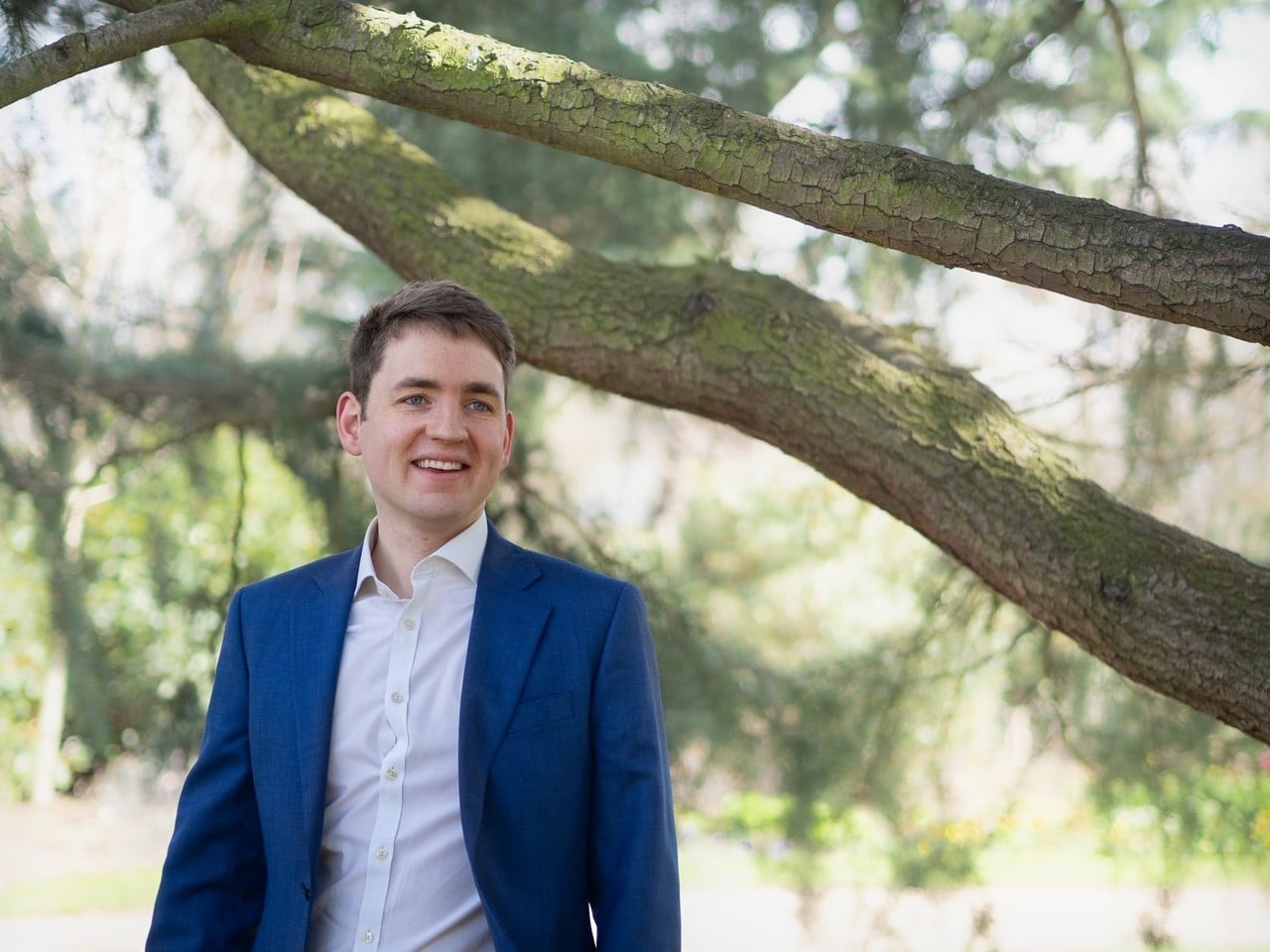 Man standing by a tree smiling.